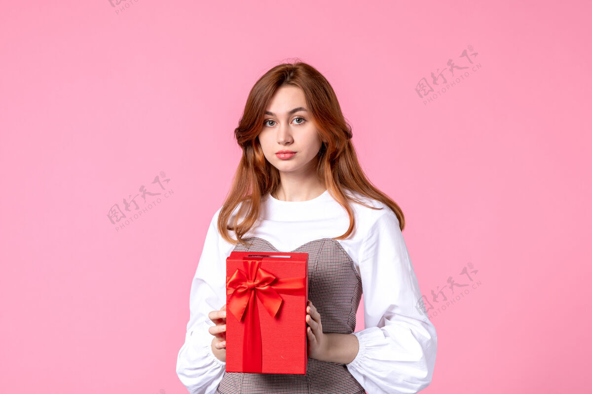 年轻女性正面图：年轻女性 红色包装 粉色背景 三月横向性感礼物 香水照片 金钱平等的女人礼品香水礼品
