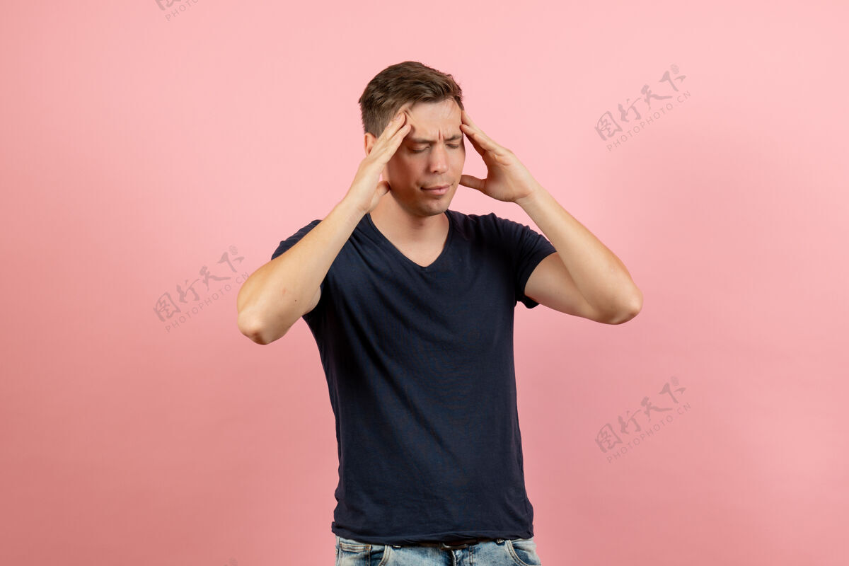 正面正面图穿着深蓝色衬衫的年轻男性在粉色背景上有点头痛男性模特色彩情感男深蓝色视图情感
