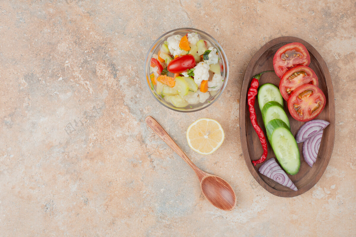 可口美味的蔬菜放在玻璃盘上 番茄 黄瓜和洋葱的木板放在大理石上黄瓜汤匙玻璃杯