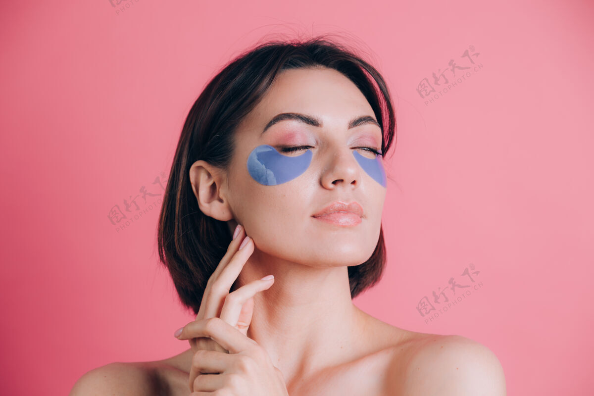 自我护理一位美丽的年轻女子的特写肖像 赤裸上身 双肩张开 眼睛下面有蓝色的胶原蛋白垫美丽的概念贴片新鲜胶原蛋白