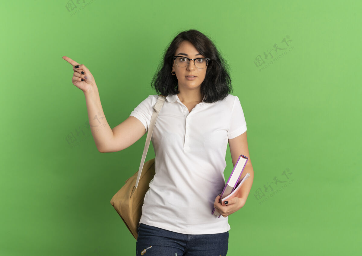 复制年轻漂亮的白人女生戴着眼镜 背着书包点在一旁 手里拿着一本绿色的书 上面留着复印空间壁板点年轻