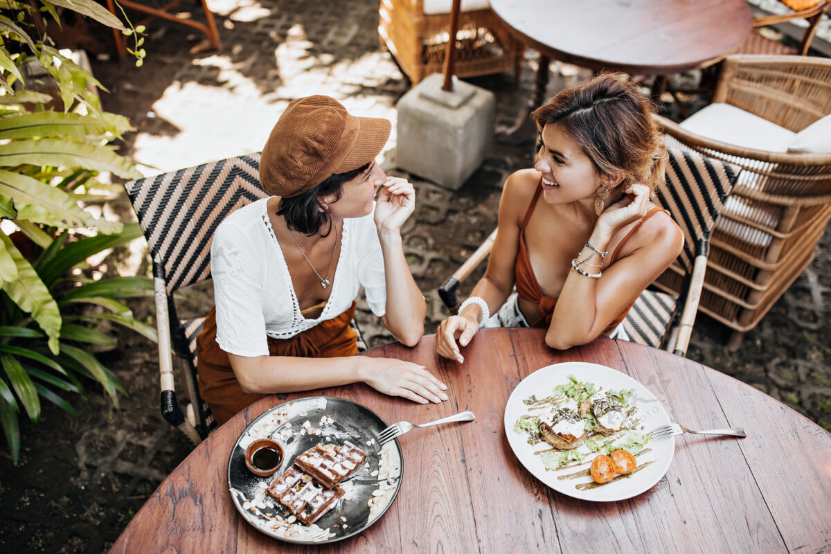 女性从上面看 穿着时髦服装的晒黑女人们在街边咖啡馆聊天 享受美味的食物自然年轻朋友