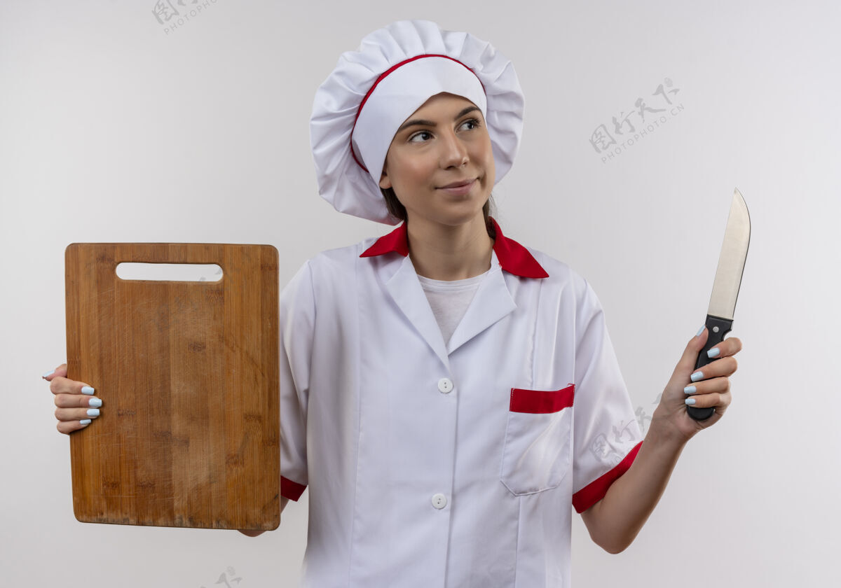板身着厨师制服的年轻快乐的白人厨师女孩手持刀和白板 留有复印空间刀制服女孩