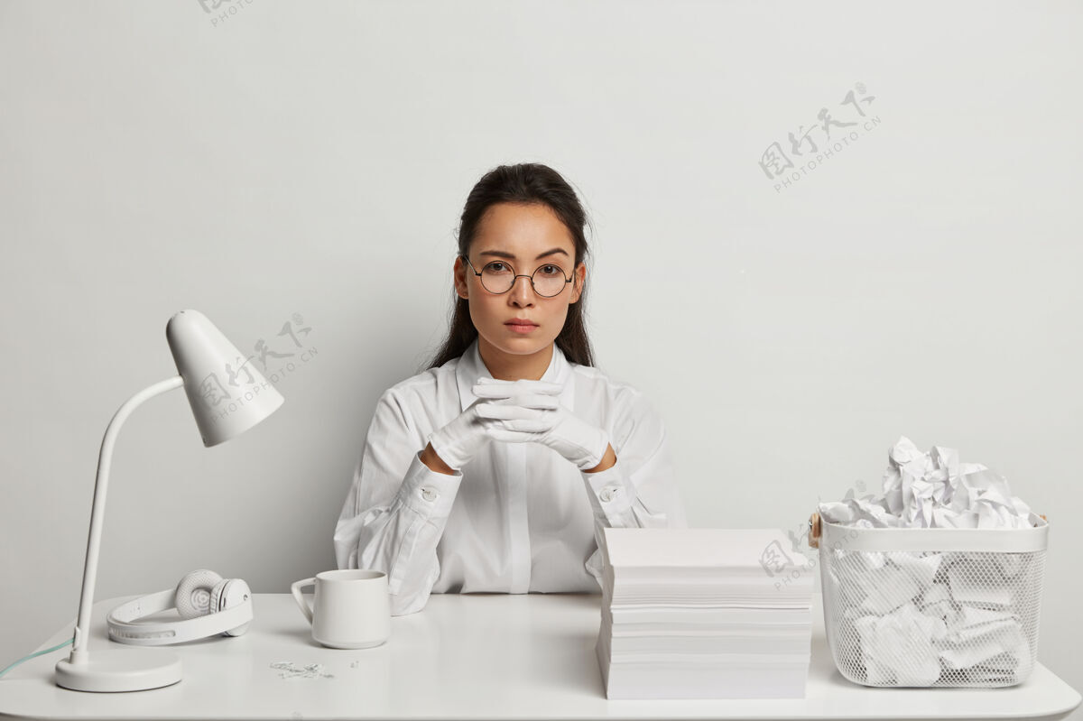 使用漂亮的年轻女子在书桌前学习耳机年轻人回形针