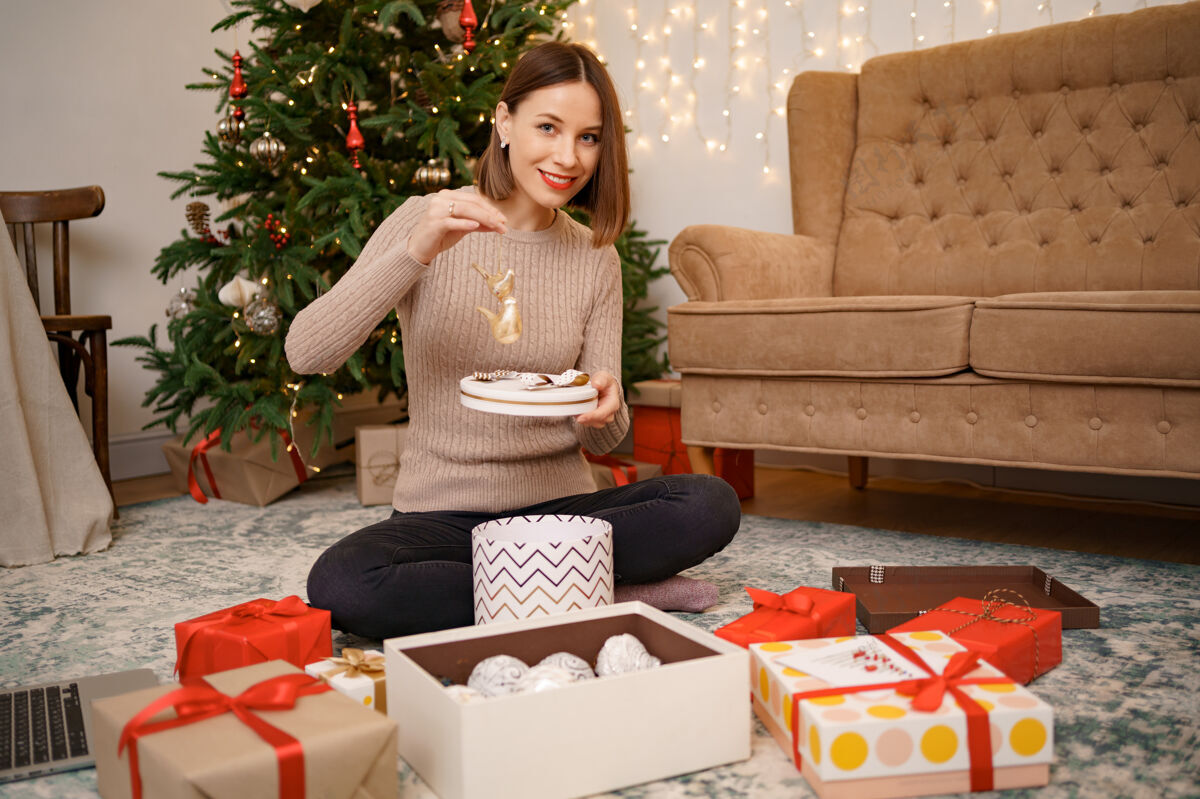 庆祝女人坐在客厅里的衣柜上包装圣诞礼物夏娃鞠躬女人