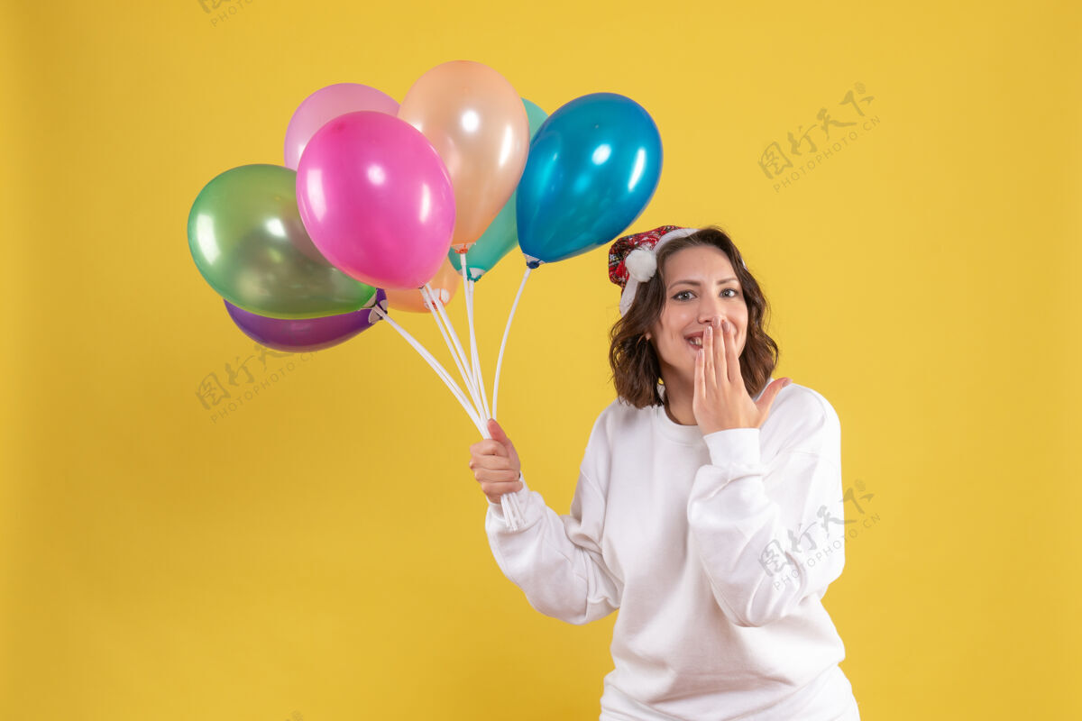 气球正面图年轻漂亮的女人拿着气球上黄色的新年情感圣诞色的女人女人正面欢呼