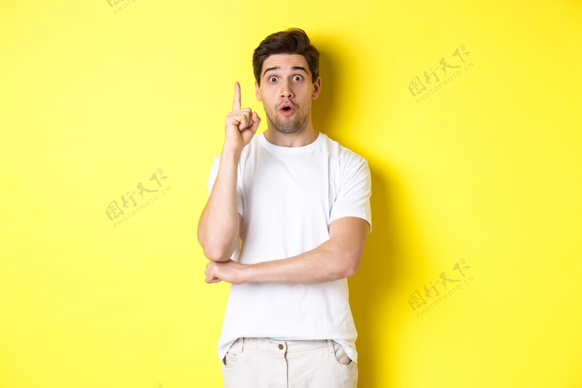 举手投足体贴的家伙建议解决方案 举起手指在尤里卡标志 看起来很兴奋 有一个想法 站在黄色的背景下自信帅哥成年人