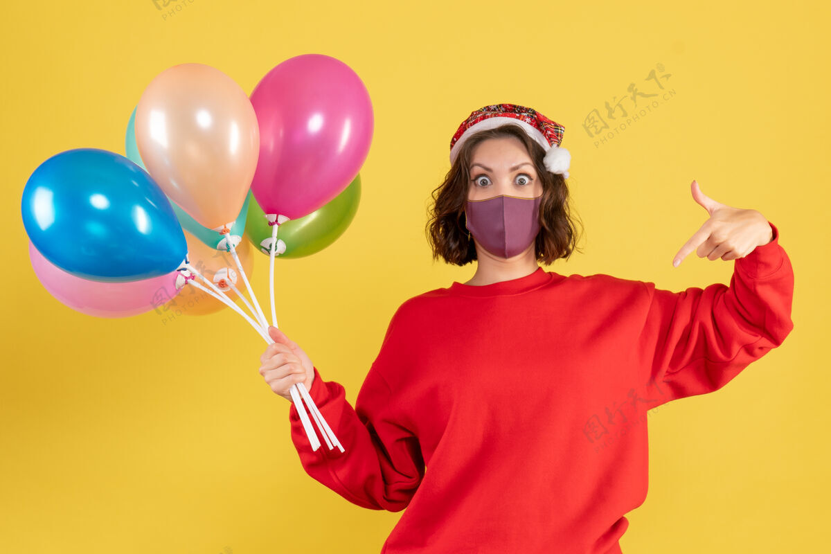 庆典正面图：戴着黄色面具手持气球的年轻女子空气派对女人