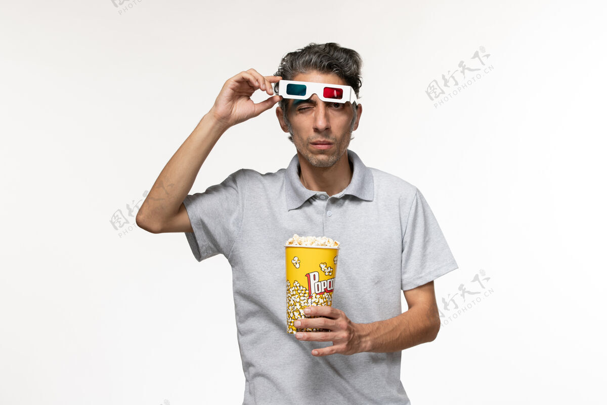 青少年正面图年轻男性手持爆米花包 戴着d型太阳镜 白色表面正面遥控护目镜