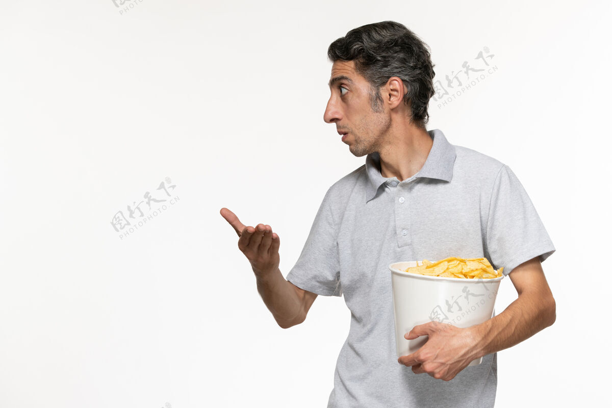 抱着正面图：年轻的男性拿着一个装薯片的篮子 和一个坐在白色桌子上的人说话书桌某人远程