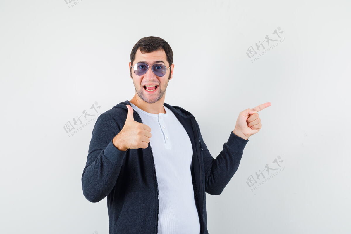 成年人身穿t恤衫的年轻男性 夹克衫指向一边 竖起大拇指 看上去很乐观 正面朝上花花公子肖像前面