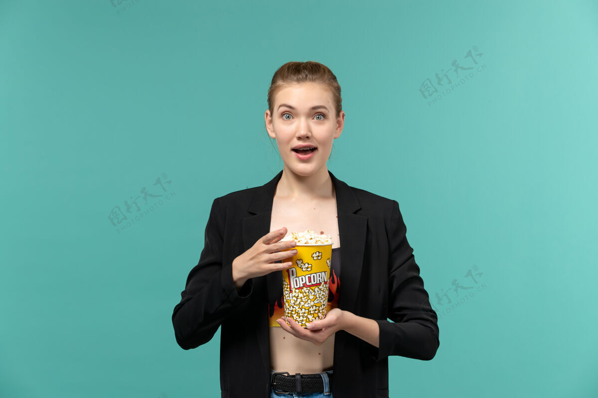 前正面图：年轻女子手持爆米花 在蓝色的水面上看电影专业电影院电影