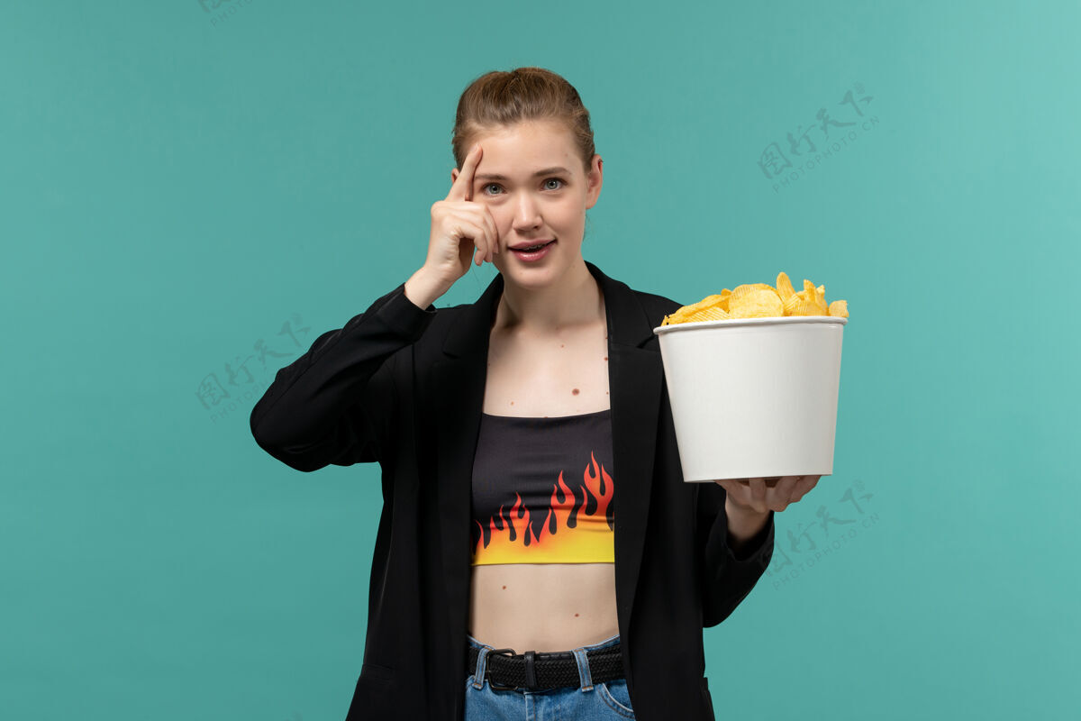 土豆正面图：年轻女性在蓝色桌子上吃薯片看电影看书桌电影院