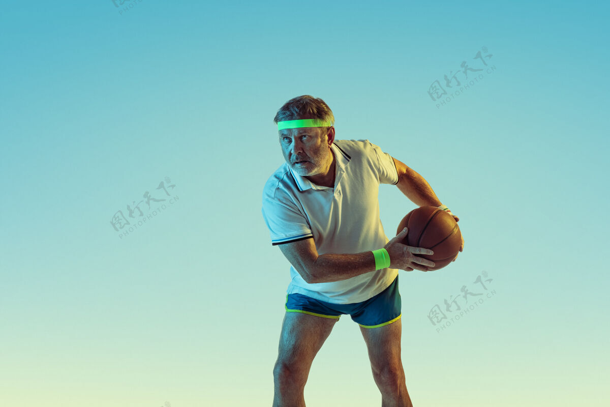 网球资深男子在霓虹灯下的斜坡墙上打篮球业余娱乐球拍