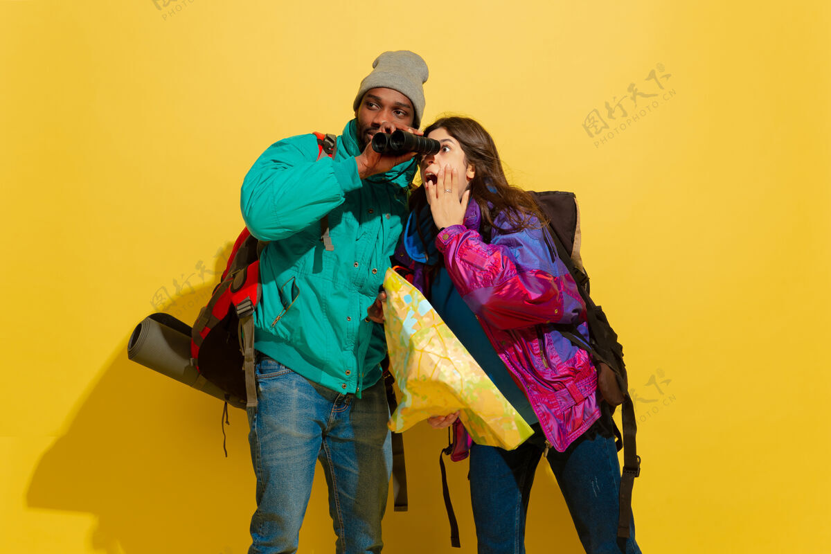 爱一对快乐的年轻旅游夫妇的画像 他们的包被隔离在黄色的工作室墙上旅行欢呼朋友