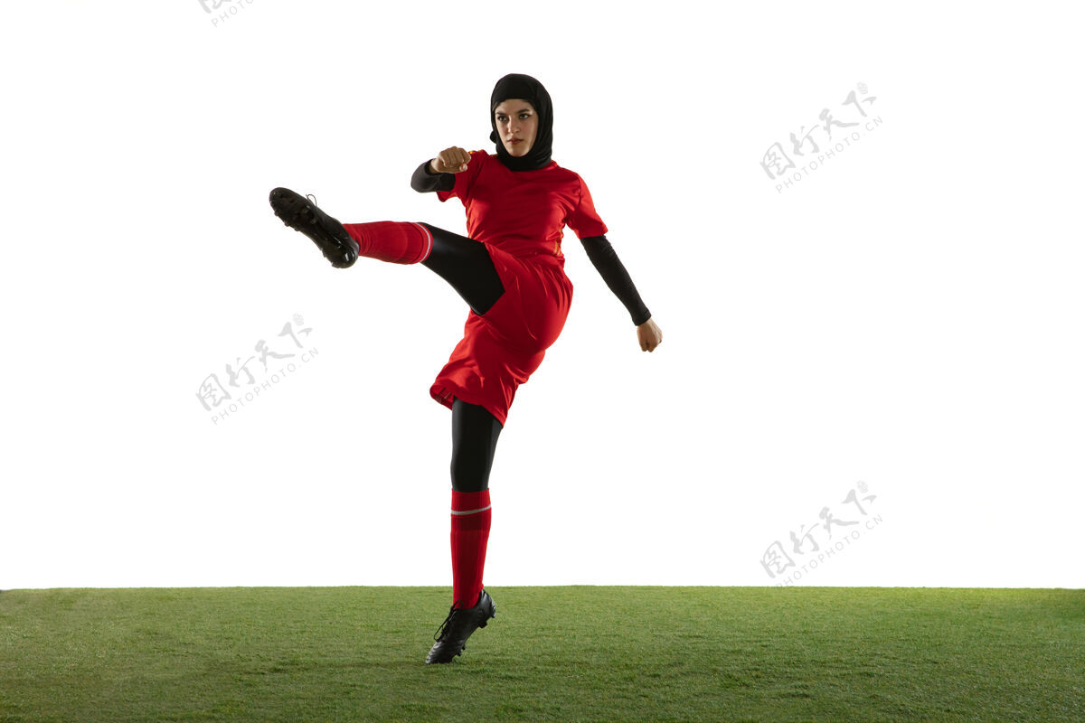抱持被隔离在白色工作室墙上的阿拉伯女足球运动员装备美丽运动员