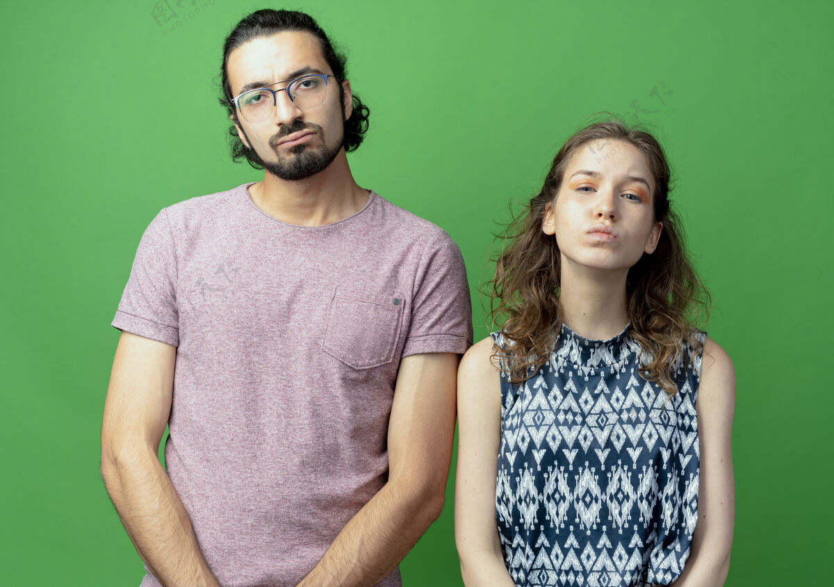 男人一对年轻夫妇站在绿色的墙上 脸上带着悲伤的表情女人悲伤夫妻