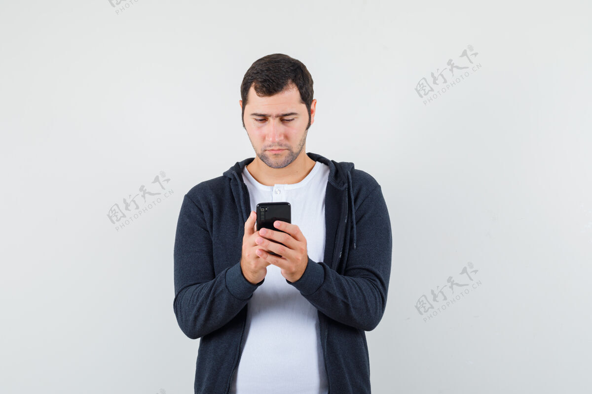电话男青年穿着t恤衫 夹克衫 用手机 看上去很忙 前视图夹克使用时尚