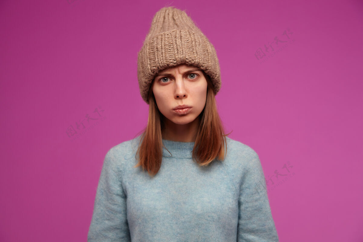 女孩眉头紧锁的肖像 一头深色长发的年轻女子 穿着蓝色毛衣 戴着针织帽子肤色严肃的表情年轻人