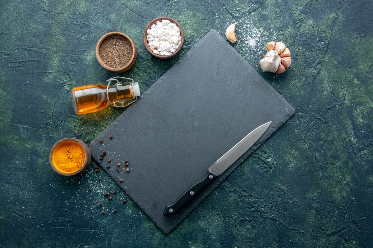 胡椒顶视图不同的调味料用油刀在深蓝色的背景上食用香料胡椒菜晚餐肉色盐烤刀肉容器