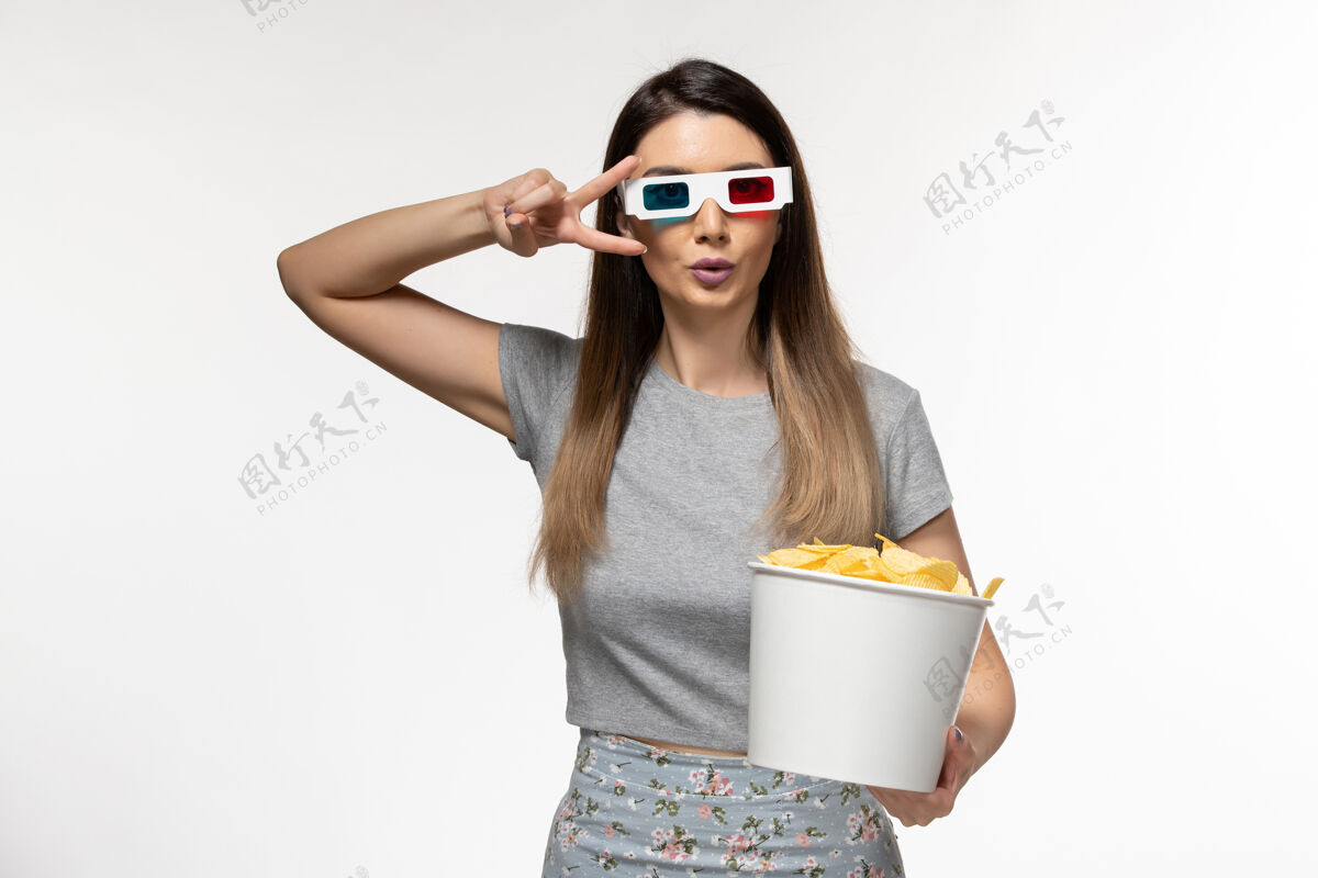 电影院正面图年轻女性手持芯片 戴着d型太阳镜在浅白色表面看电影漂亮的太阳镜而