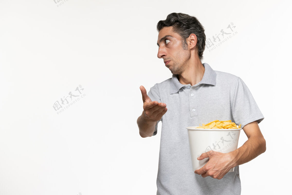 电影院正面图：年轻的男性拿着一个装薯片的篮子 和一个坐在白色桌子上的人说话电影土豆某人