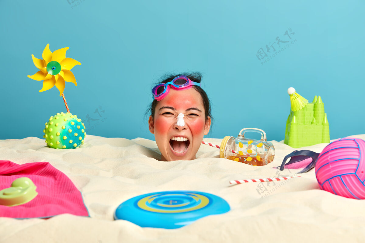 喊叫年轻女子头上涂着防晒霜 脸上围着沙滩饰品度假女人日光浴