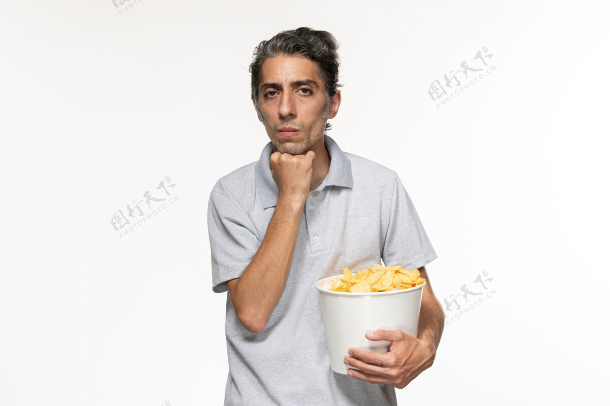 电影正面图：年轻的男性拿着土豆片的篮子在白色的表面思考孤独电影专业