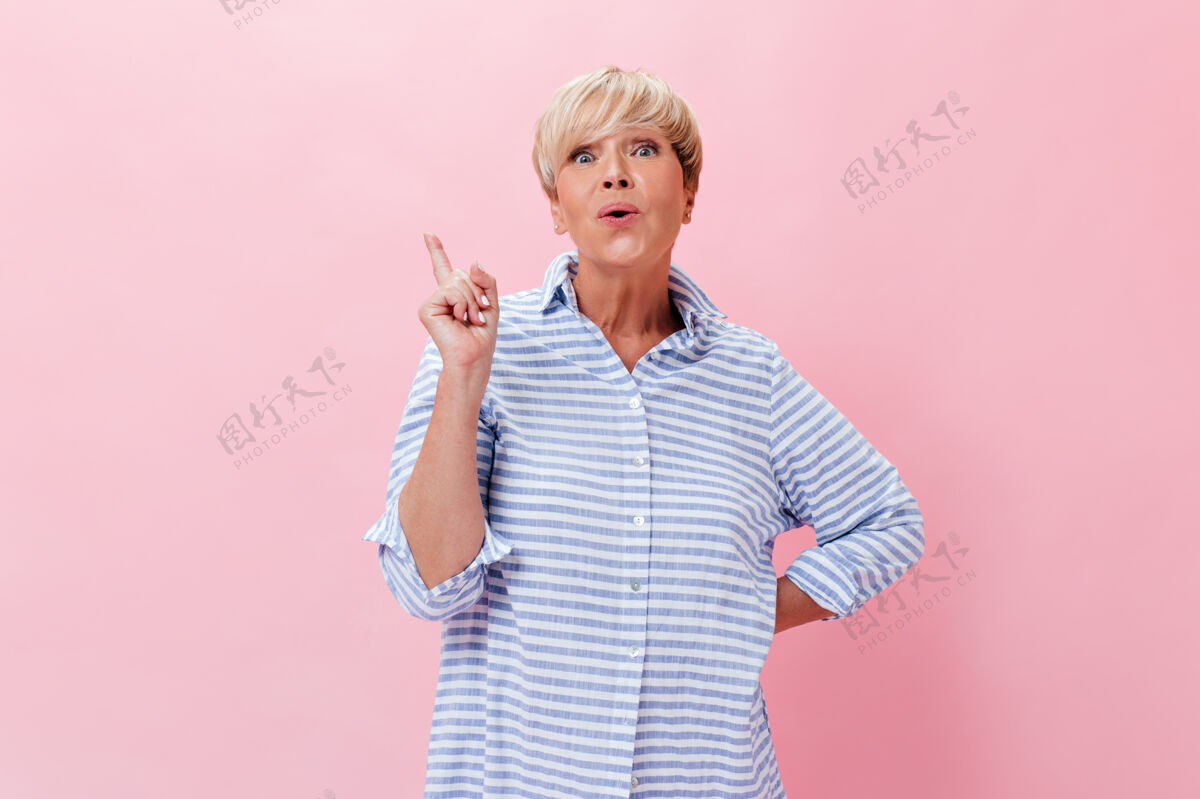 朋友身着蓝色套装的迷人女人有了主意 在粉色背景下看着镜头健康老年人人