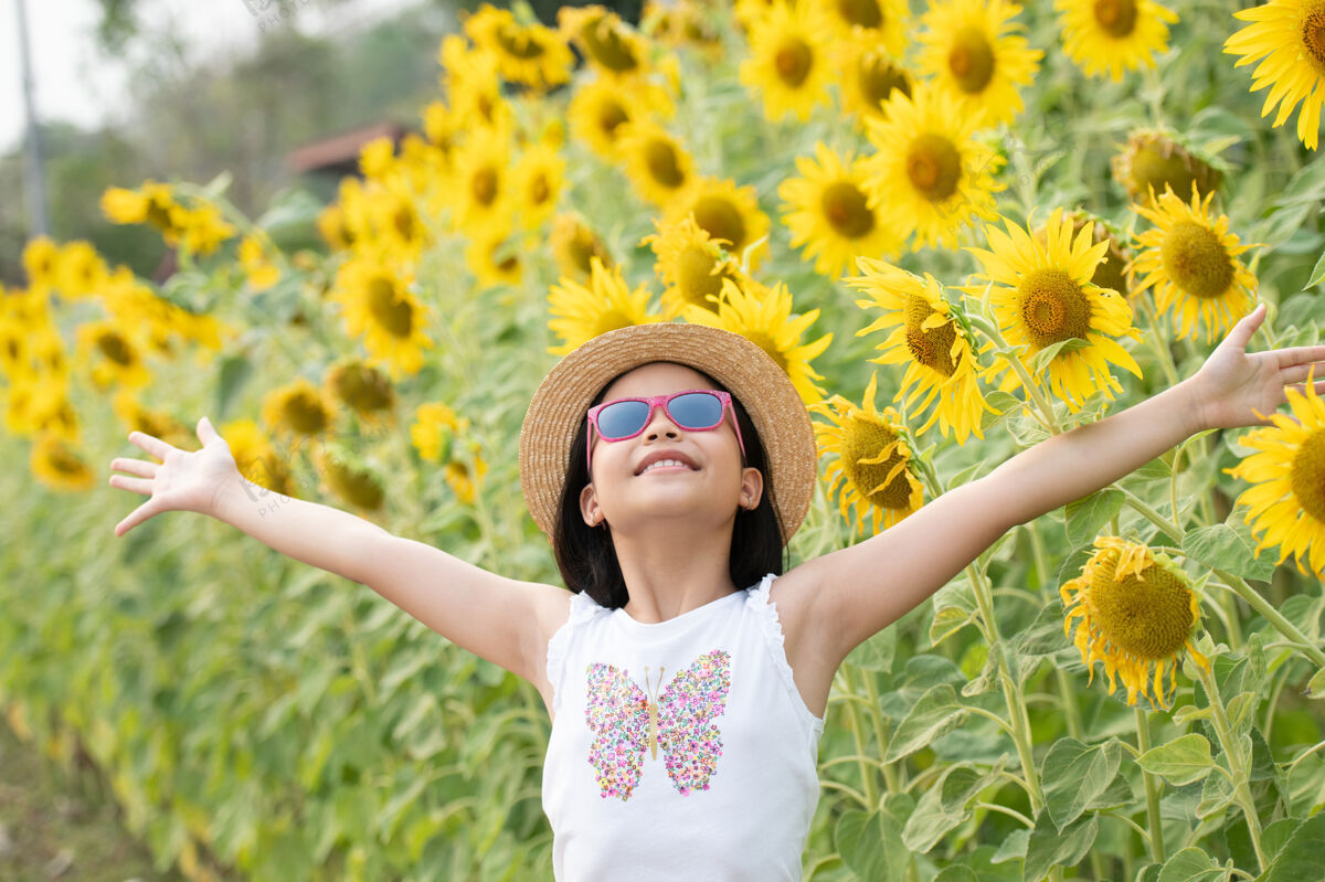 乐趣快乐的亚洲小女孩在阳光下 在盛开的向日葵中嬉戏微笑快乐太阳