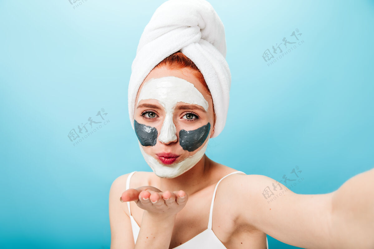 清洁面部快乐的白种女孩戴着口罩送空气吻美丽的女士做护肤治疗和自拍女性皮肤护理女孩