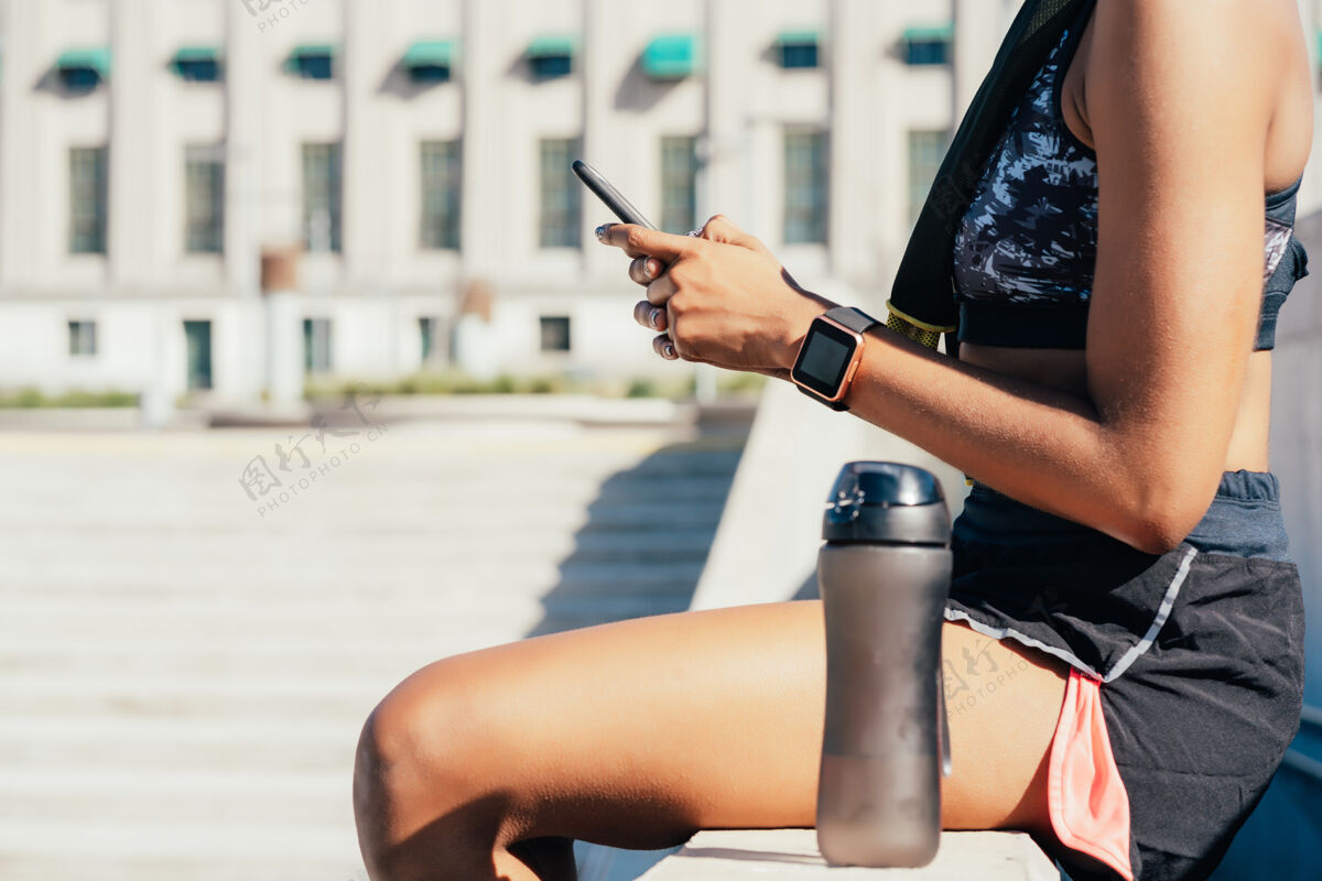 健身房运动型女性在户外运动后使用手机和放松运动和健康的生活方式运动健身瓶子
