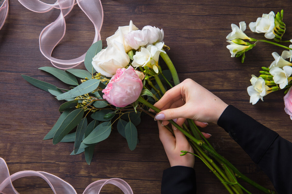花卉工作中的花店：在木桌上制作不同花朵的时尚现代花束的女人广告花店束
