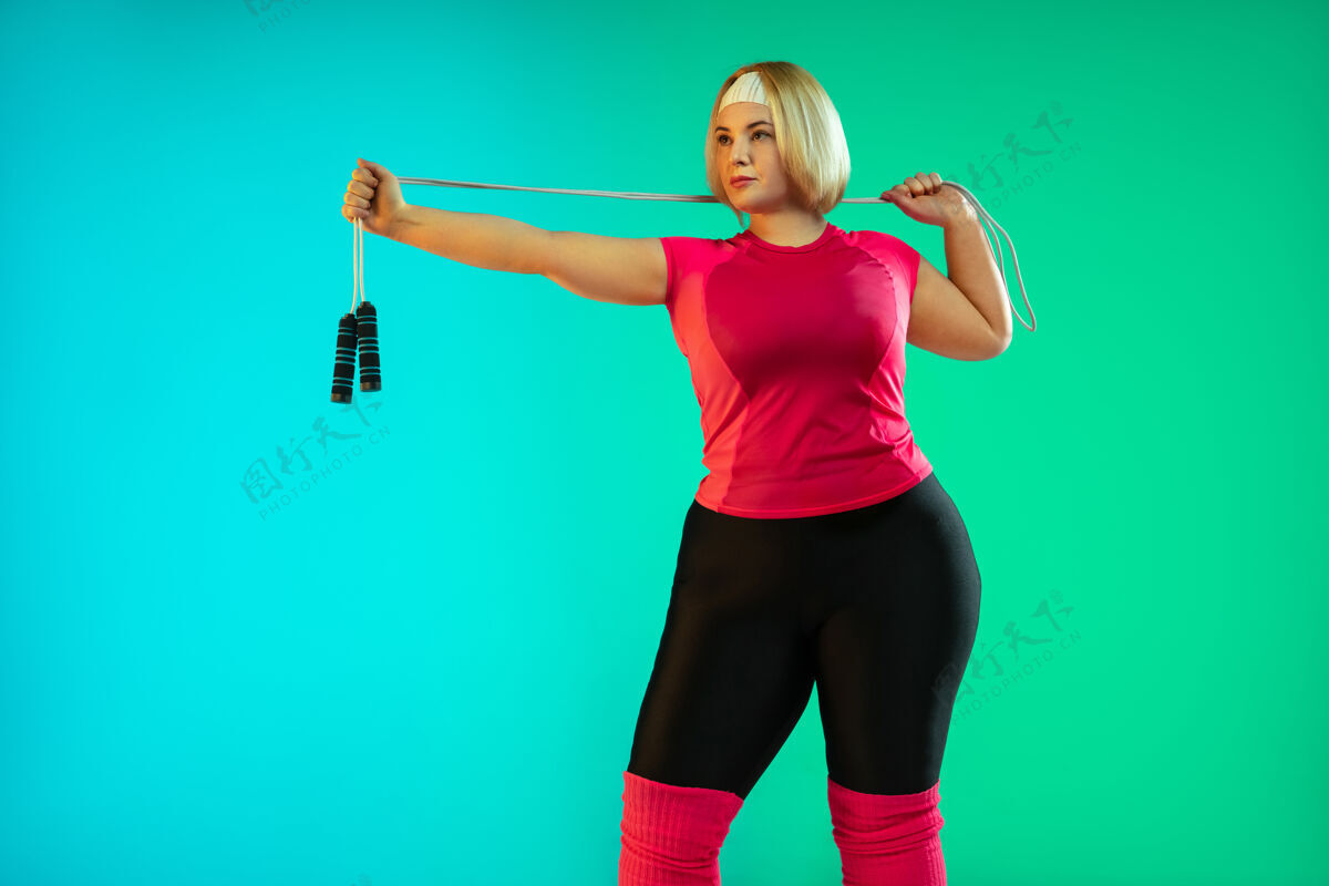 大小年轻的白人大号女模特在霓虹灯下的梯度绿色背景下训练跳绳锻炼运动理念 健康的生活方式 积极的身体 平等专业拉伸超重