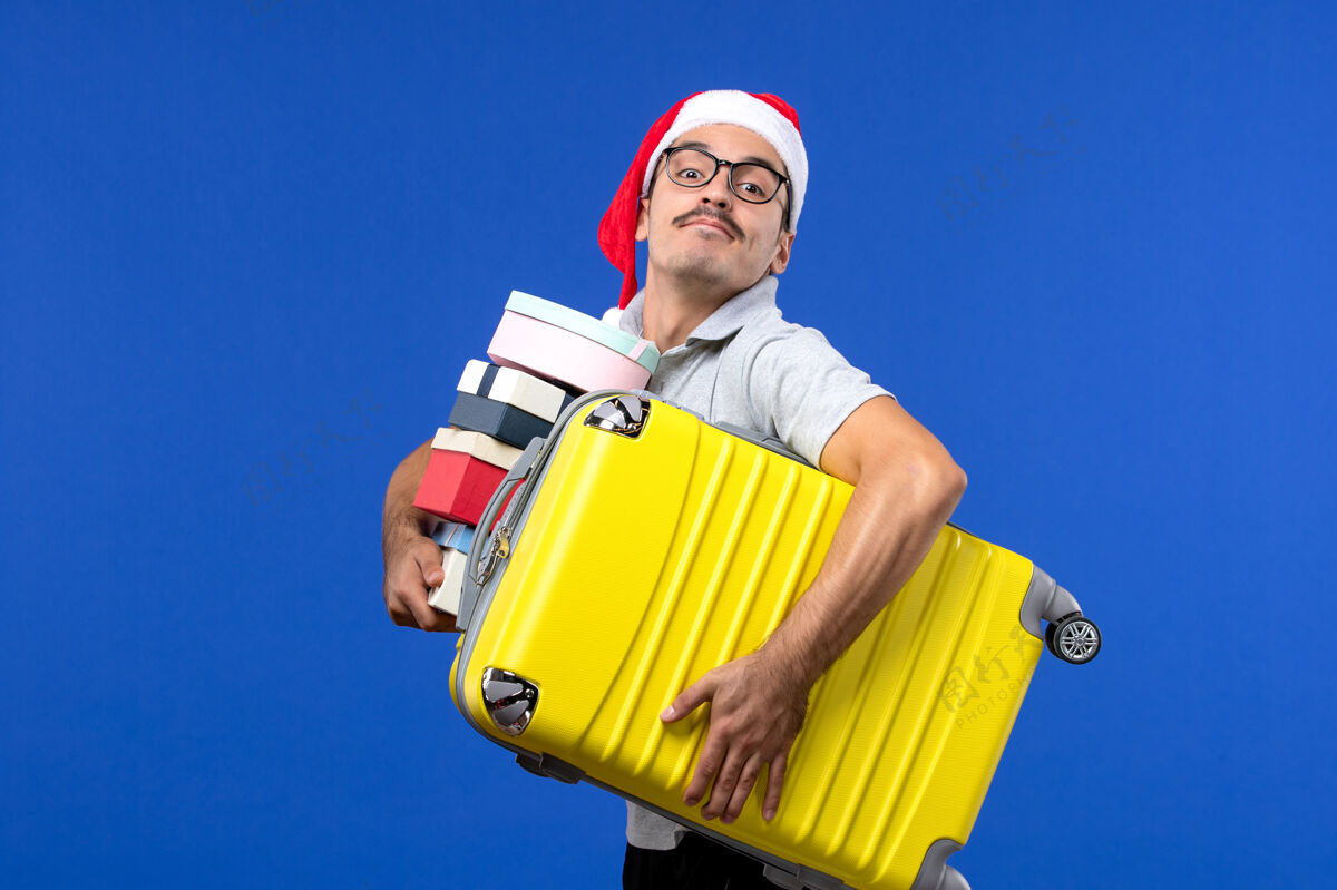工作前视图年轻男性携带包和礼物的蓝色办公桌飞行度假飞机圣诞节度假区包