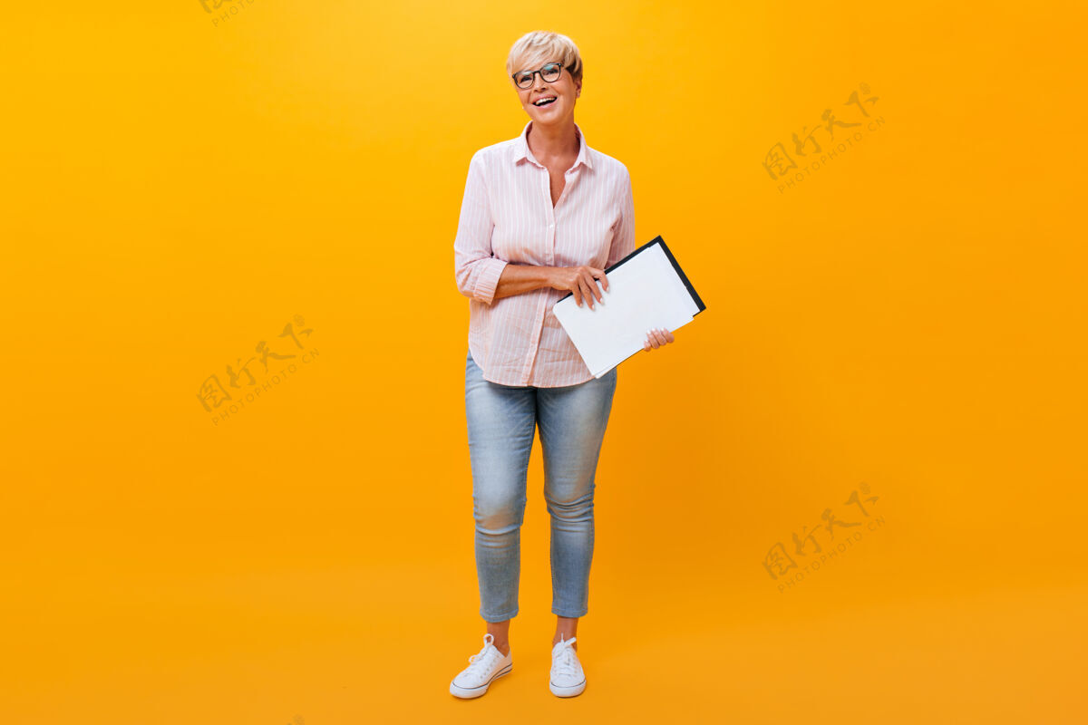 休闲身着牛仔裤和衬衫的商业女士的肖像 橙色背景漂亮老年人老年
