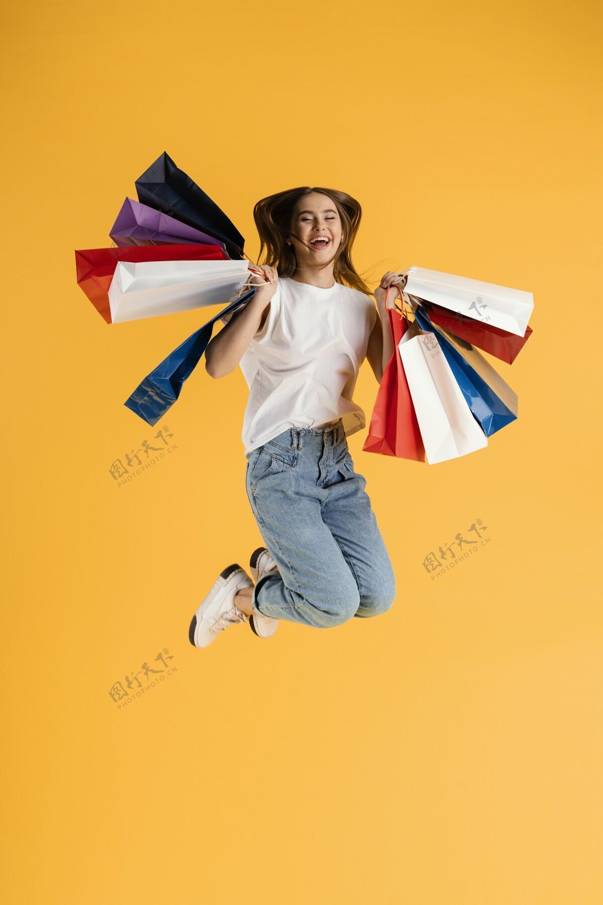 女带着购物袋跳跃的年轻女性肖像跳跃肖像购物袋