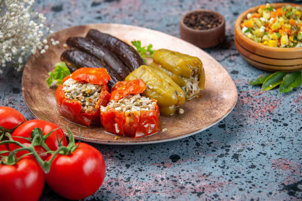里面前视图茄子与煮熟的西红柿和甜椒与肉末填充在蓝色背景板内多尔玛晚餐胡椒粉盘子