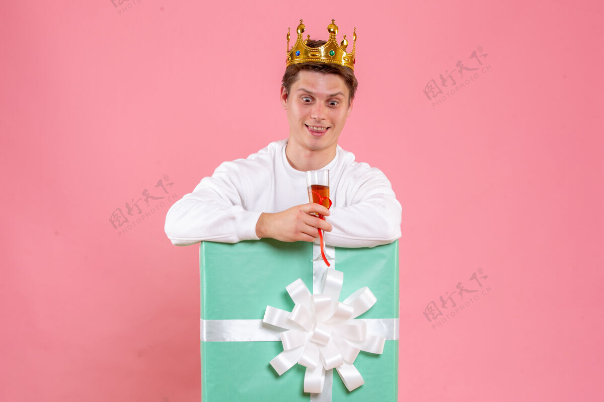 风景正面图：年轻男性 戴着皇冠 一杯酒 背景为粉色情感圣诞皇冠