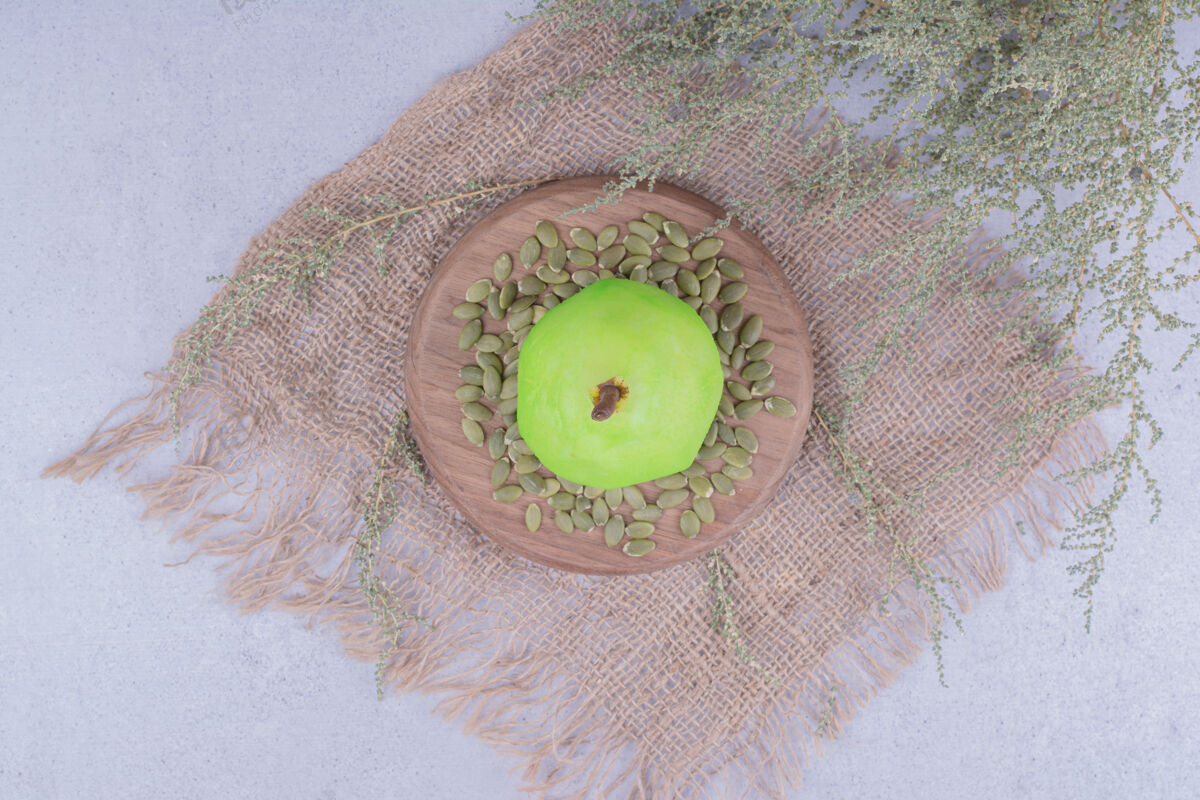 甜味一个绿色的梨放在木板上 上面有南瓜子酸味清淡生物