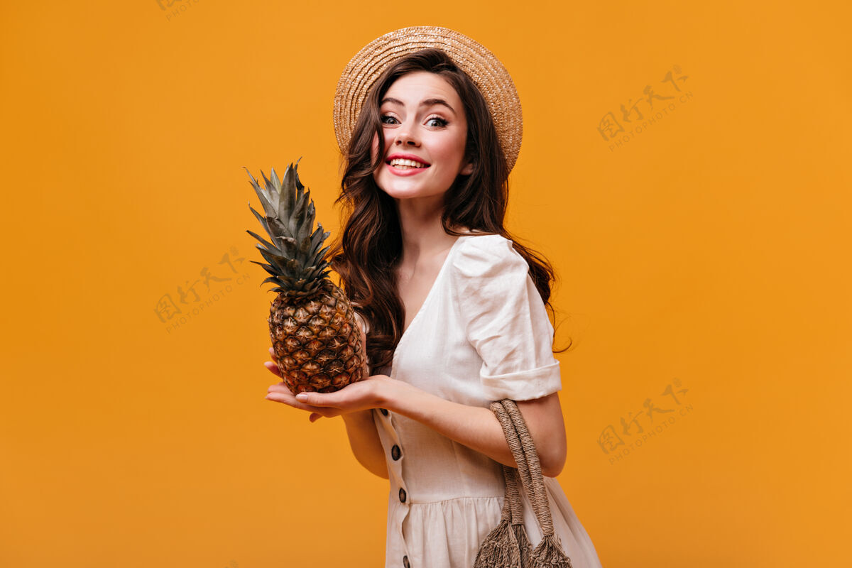 化妆品穿着棉衣的漂亮女人微笑着看着镜头 在孤立的背景下摆出菠萝的姿势船夫卷发肖像