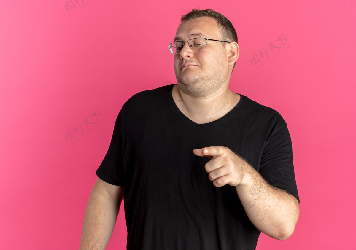 看戴眼镜的超重男子身穿黑色t恤 看上去自信满满 食指指向粉色上方的一侧粉色信心超重