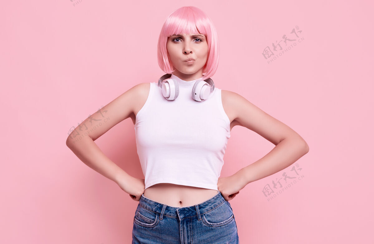 肖像美丽明亮的潮人女孩的肖像与粉红色的头发享受音乐在耳机上五颜六色香草娱乐耳机