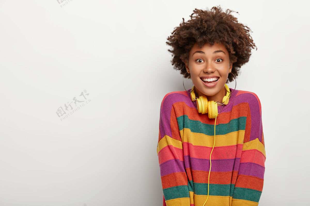 肖像快乐的千禧一代非洲女孩的肖像享受业余时间 通过耳机听音乐 看着你高兴快乐时尚套头衫