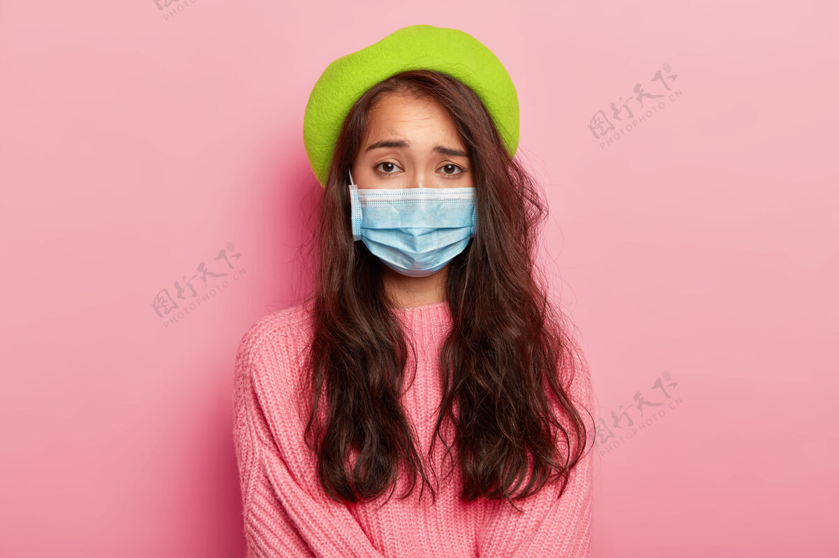 不安不满的年轻女模特戴着医用口罩 身患重病 来医院看病 有病毒感染 戴着绿色贝雷帽和套头衫病毒时尚人