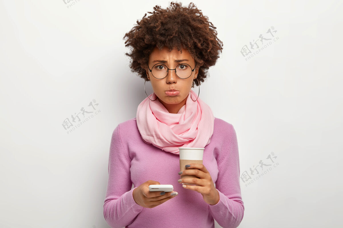 站着不开心的女人捂着下唇 因男友不及时打电话而感到沮丧 举着办约会的手机 喝外卖咖啡社交短信心烦