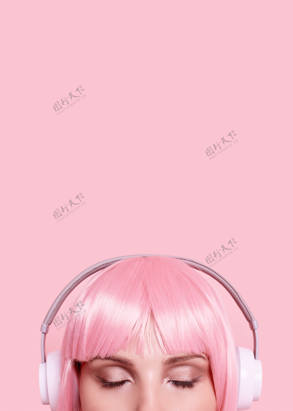 微笑粉红头发的美女肖像在耳机里欣赏音乐美丽时尚美女