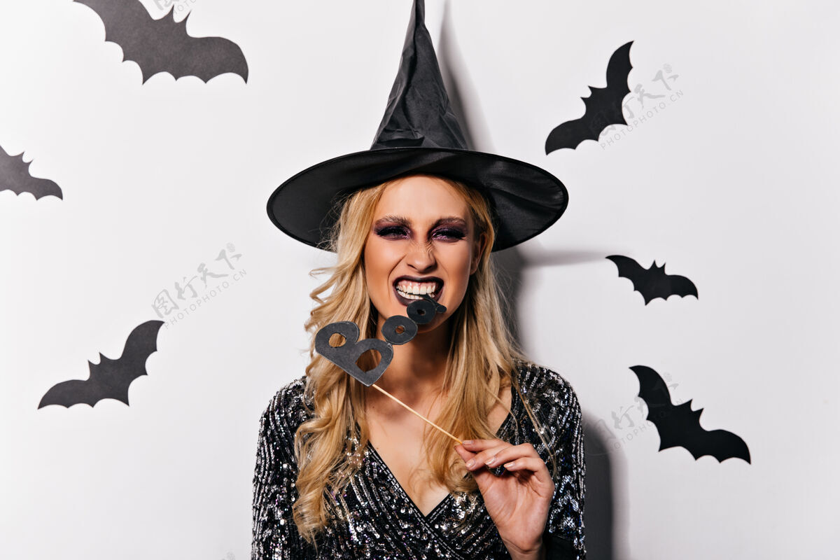 魔术师带着波浪发型的女巫庆祝万圣节戴着滑稽帽子的欣喜若狂的女吸血鬼与蝙蝠合影幻想庆典恐惧