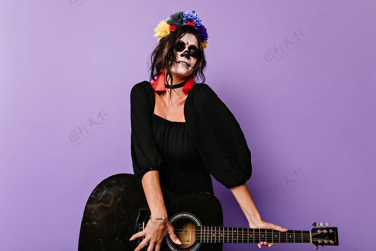 服装兴奋的僵尸女孩弹吉他穿着万圣节黑色服装的高加索女人玩得很开心女孩恐怖肖像