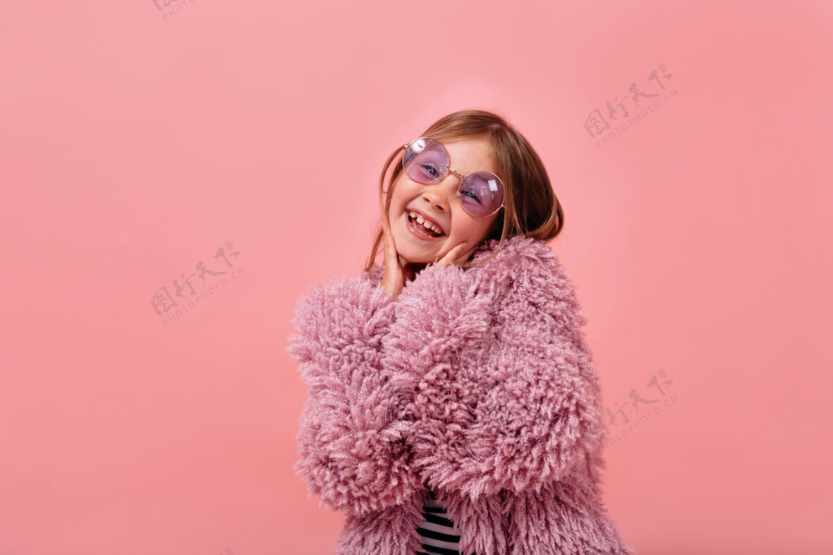 外套迷人的漂亮女孩 6岁 穿着紫罗兰色皮草 戴着圆眼镜 摆出快乐的姿势魅力小女孩时尚